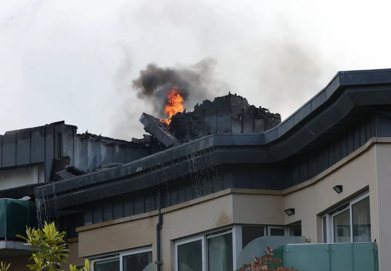 Fire engulfing the rooftop of a modern building with smoke billowing into the sky